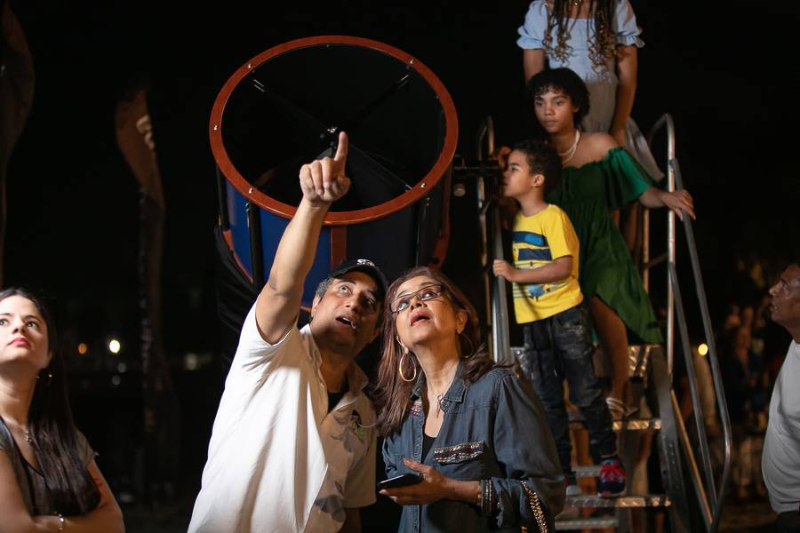 Niños y adultos señalan el cielo junto a un telescopio grande