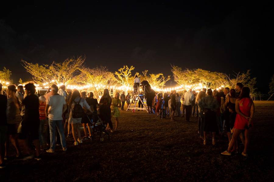 Jardín iluminado con luces cálidas y personas reunidas de noche