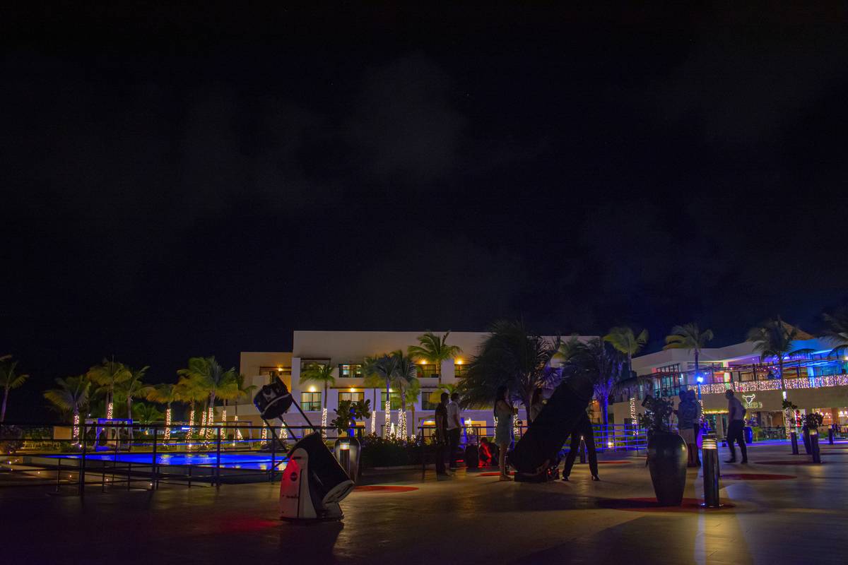 Telescopios de M42 instalados de noche frente a un hotel iluminado junto al agua