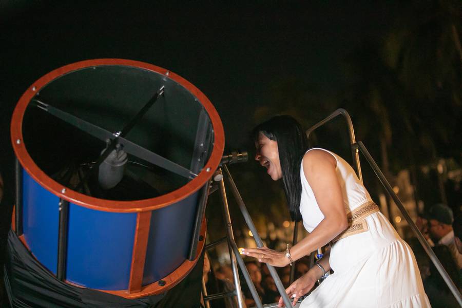 Una mujer con vestido blanco mira por el telescopio grande de M42 en un evento nocturno