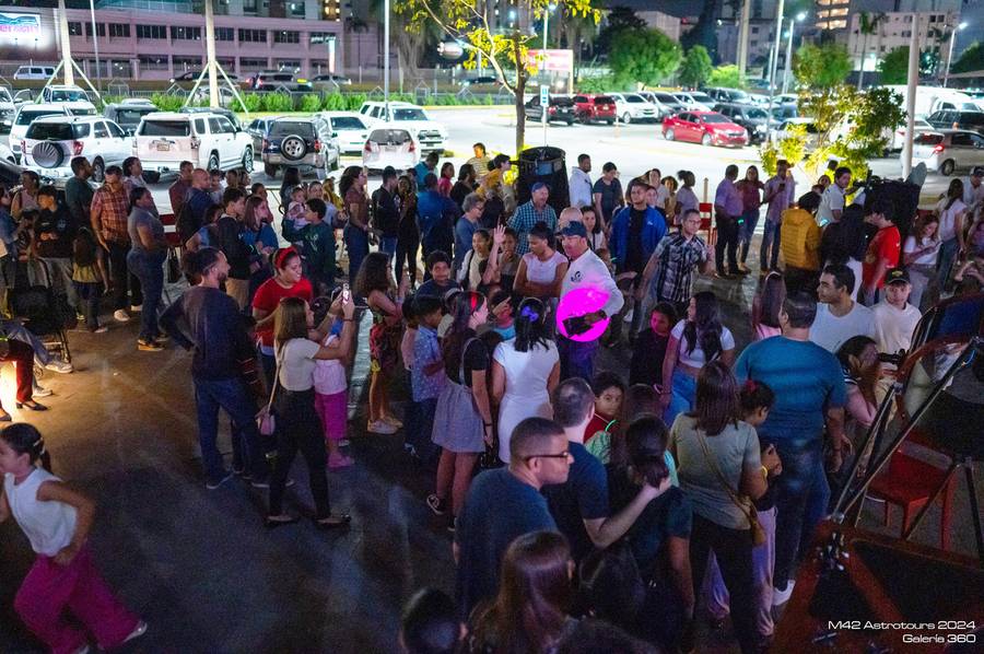 Multitud en una plaza comercial haciendo fila para mirar por varios telescopios