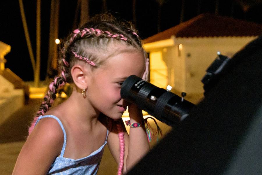 Una niña con trenzas mira por el ocular de un telescopio